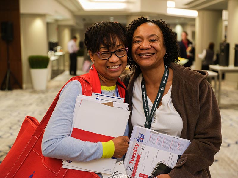 Photo of two happy African American women holding conference materials